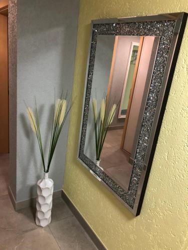 a mirror on a wall next to a vase with flowers at Gästehaus Alwin Diebold - 5 Gehminuten zum Europapark in Rust