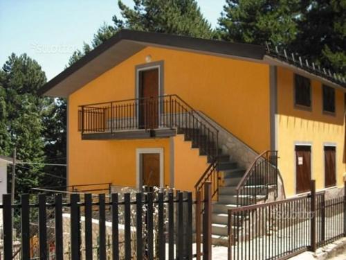 カミリアテッロ・シラーノにあるVilletta lo Scoiattoloの階段と柵のある小さな黄色の家