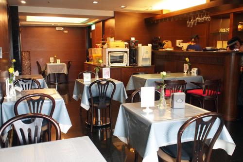 a restaurant with white tables and chairs and a kitchen at Burgary Hotel in Taipei