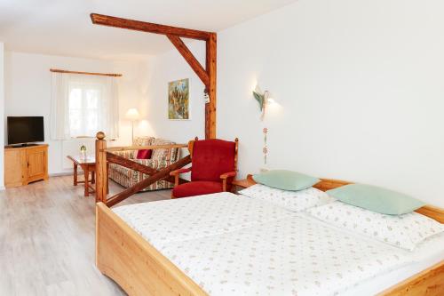a bedroom with a bed and a red chair at Hotel Garni Schöne Aussichten in Klöch