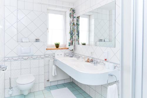 a white bathroom with a sink and a toilet at Hotel Garni Schöne Aussichten in Klöch
