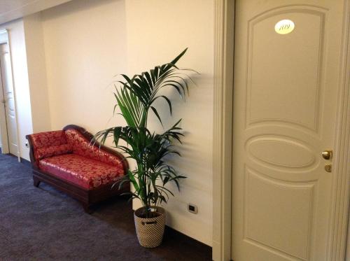 a living room with a red chair and a plant at Palace Hotel & SPA La CONCHIGLIA D' ORO in Vicenza