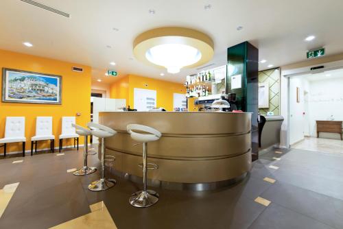 a bar with stools in a restaurant with yellow walls at Palace Hotel & SPA La CONCHIGLIA D' ORO in Vicenza