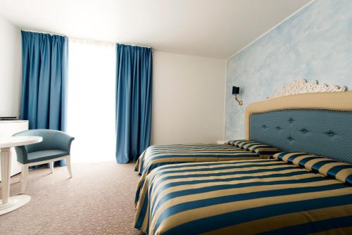 a hotel room with a bed with a striped bedspread at Palace Hotel & SPA La CONCHIGLIA D' ORO in Vicenza