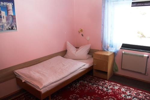 a small room with a bed and a window at Penzion Gentiana in Desná