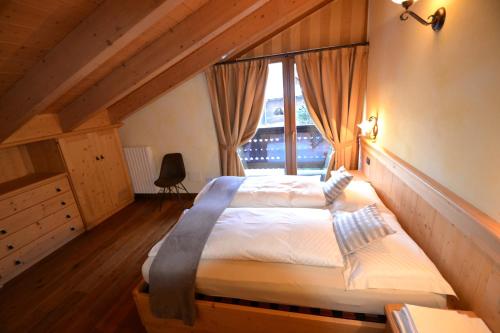 1 dormitorio con 1 cama grande y ventana en Casa Urbani, en Livigno