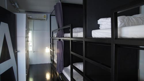 a room with three bunk beds with white sheets at The PARK Society in Chiang Mai
