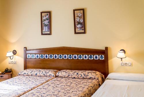 a bedroom with two beds and two pictures on the wall at Cortijo De Tajar in Huétor-Tájar