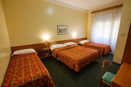 a hotel room with three beds and a window at Hotel Adriatic in Rome