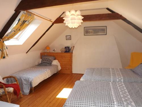 2 camas num quarto no sótão com um lustre em Gite De Penn Ar Stank em Pont-de-Buis