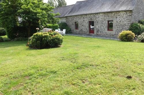 a stone house with a yard with a grass field at Gite De Penn Ar Stank in Pont-de-Buis