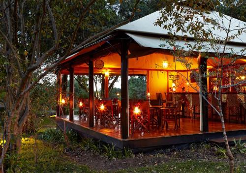 a house with a deck with a table and chairs at Olare Mara Kempinski in Talek