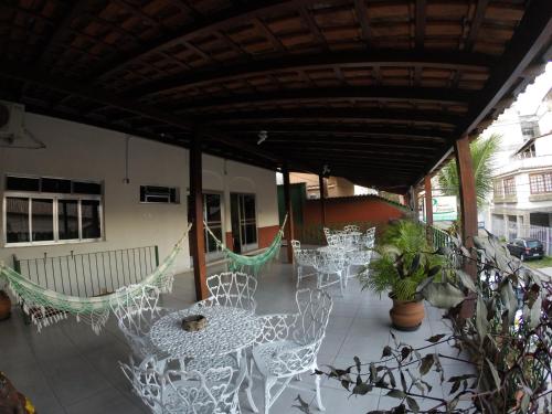 un patio con sedie bianche, tavoli e amache di Pousada Casagrande - São João a Volta Redonda