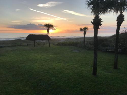 a sunset over the ocean with palm trees in a field at South Beach Inn - Cocoa Beach in Cocoa Beach