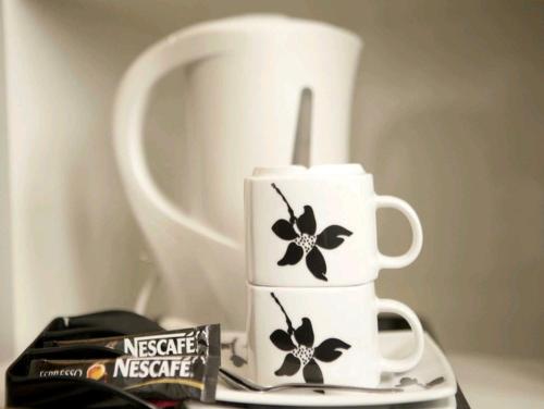 a white coffee maker with black flowers on a table at Laman Kurnia Holiday House in Kota Bharu