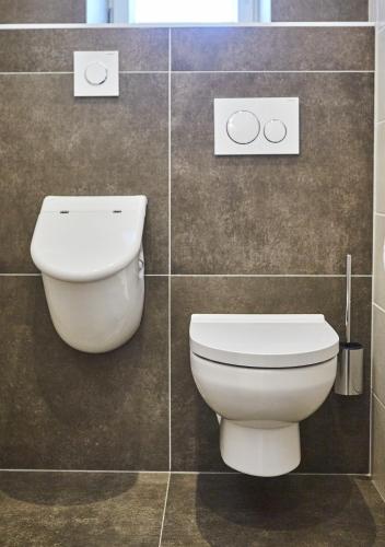 a bathroom with a toilet in a tiled wall at Holiday Penthouse Moosweg in Maishofen