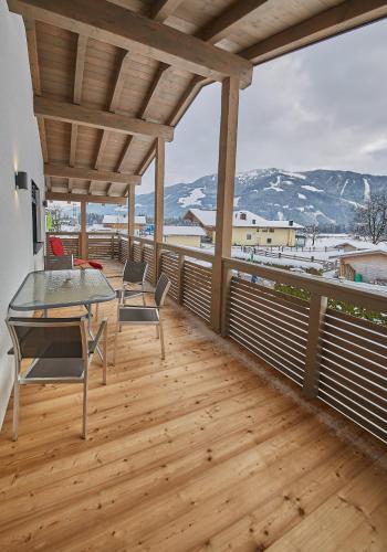 a patio with a table and chairs on a wooden deck at Holiday Penthouse Moosweg in Maishofen