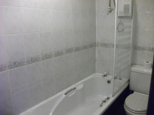 a bathroom with a white tub and a toilet at The Lantern Pike Inn in Hayfield