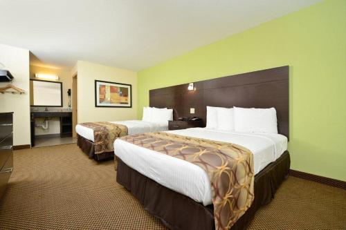 Cette chambre comprend deux lits et une télévision. dans l'établissement Americas Best Value Inn Lake Charles Interstate 210, à Lake Charles
