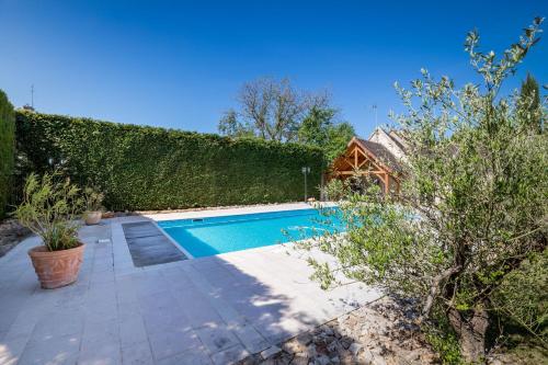 une piscine dans un jardin à côté d'une haie dans l'établissement Le Jardin De Maurice, à Sainte-Marie-la-Blanche