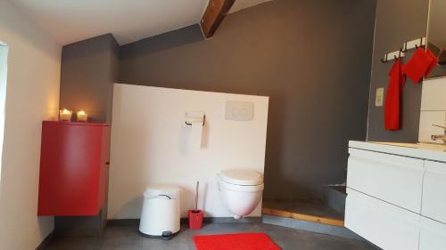 uma casa de banho com um WC e um armário vermelho em Au calme em Marchin