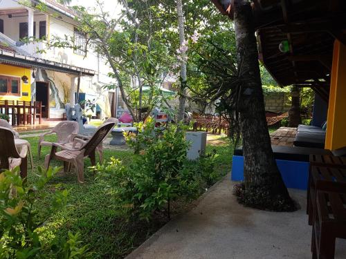 a yard with chairs and tables and a tree at Plantation Surf Inn & Restaurant - Midigama in Midigama
