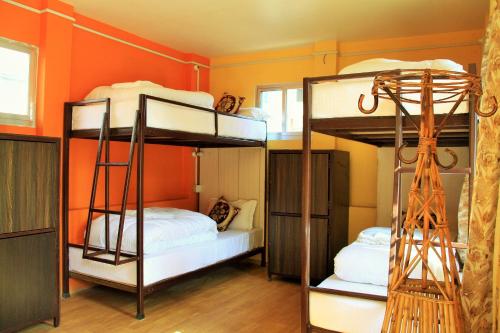 Ce lit se trouve dans un dortoir doté de 2 lits superposés et d'un mur orange. dans l'établissement Kathmandu Village House, à Katmandou