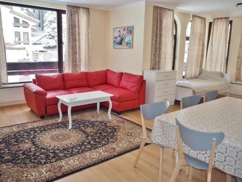 パンポロボにあるFirefly Apartments Pamporovoのリビングルーム(赤いソファ、テーブル付)