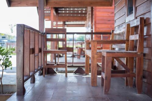 a porch with two wooden chairs and a table at Talad Nam Klong Hae Resort in Hat Yai