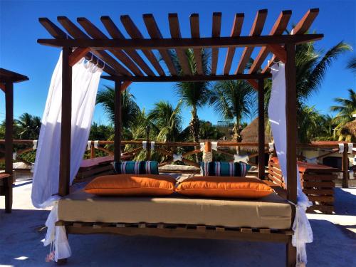a bed with pillows under a wooden gazebo at Hotel Para Ti - Adults Only in Holbox Island
