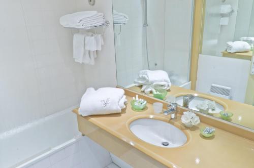 a bathroom with a sink and a mirror at Hôtel L'Yeuse - Teritoria in Châteaubernard