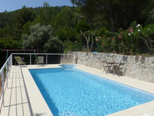 einen Pool mit Stühlen und einer Steinmauer in der Unterkunft La Nevet's in Ollioules