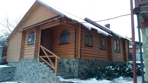 a log cabin with a staircase on the side of it at Karpatska Mria in Yaremche