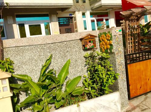 a garden with plants and a wall with a wooden door at Home & Teak Homestay in Jinning