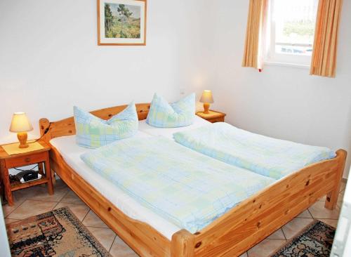 una camera con letto in legno e cuscini blu di Ferienappartements Gaude Stuv a Ostseebad Sellin