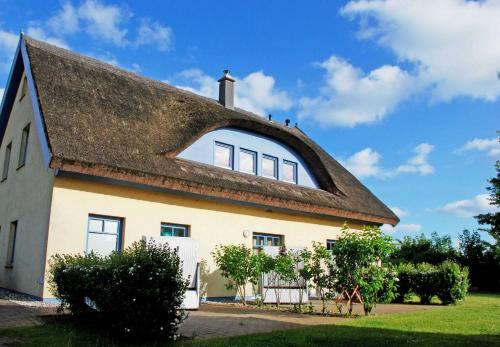 a large white house with a thatched roof at Ferienappartements Ostsee_ Nixen_ in Lobbe