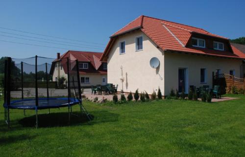 a house with a yard with a trampoline in the grass at Ferienappartements Familie Lenz in Sehlen