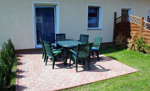 a patio with a table and chairs on the grass at Ferienappartements Familie Lenz in Sehlen
