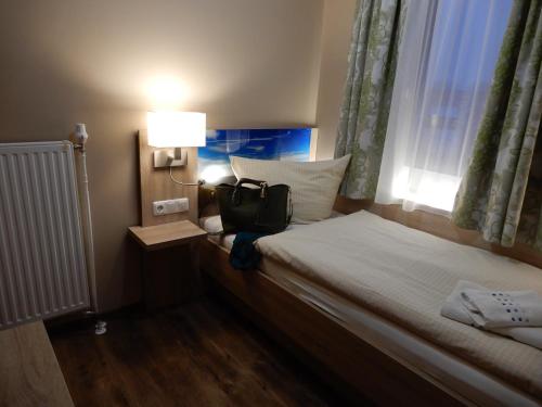 a bedroom with a bed with a bag on it at Hotel Pension Am Hafen in Norddeich