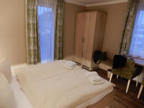 a bedroom with two beds and a desk and window at Hotel Pension Am Hafen in Norddeich