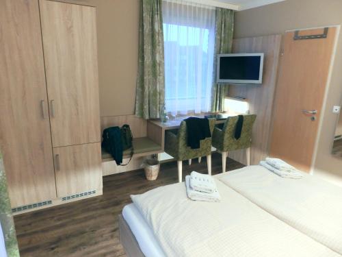 a hotel room with two beds and a desk at Hotel Pension Am Hafen in Norddeich