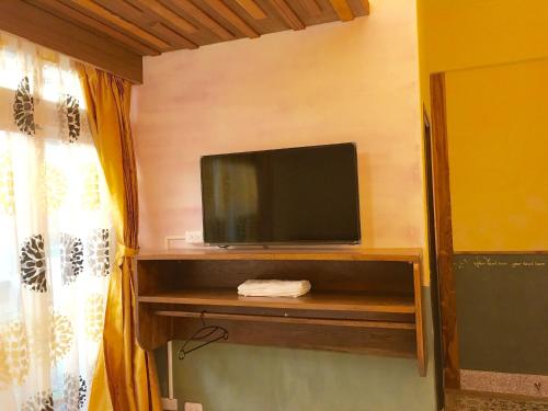 a flat screen tv sitting on a shelf in a room at Home & Teak Homestay in Jinning