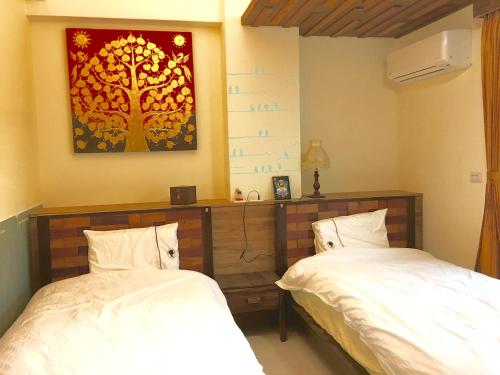 a bedroom with two beds and a painting on the wall at Home & Teak Homestay in Jinning