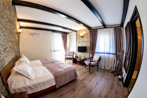 a bedroom with a bed and a room with a chair at Pensiunea Câmpia Soarelui in Apa Neagră
