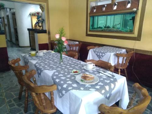 Hotel Las Rampas في ميديلين: غرفة طعام مع طاولتين وكراسي مع طبق من الطعام