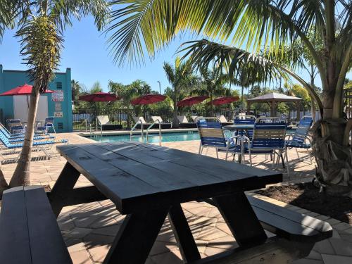 a picnic table next to a pool with chairs and umbrellas at Days Inn by Wyndham Sarasota Bay in Sarasota
