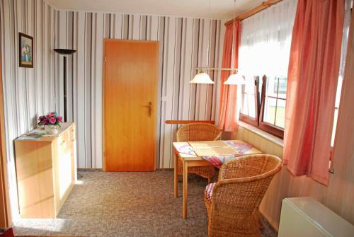 ロープベにあるFerienwohnung an der Deichwieseのテーブルと椅子、窓が備わる客室です。
