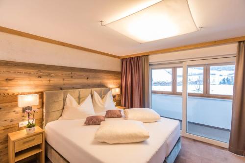 a bedroom with a large bed with a large window at Gasthof Ellmauer Hof in Ellmau