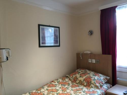 um quarto com uma cama e uma fotografia na parede em Albro House Hotel em Londres