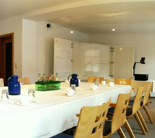 a room with a long table with chairs and a whiteboard at Querfurter Hof in Querfurt